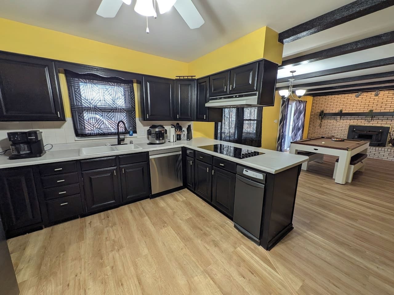 Una cocina moderna con gabinetes negros, encimera blanca y lavavajillas empotrado.