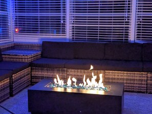 Un área de estar exterior moderna con una chimenea integrada.