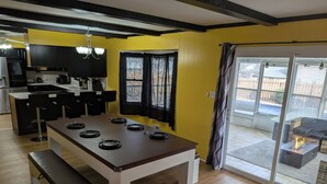 A modern kitchen with black cabinets, a dining table with black plates, and a bench. - 5BR Home, Pool + Game Room -- Sleeps 16+ (Evansville)