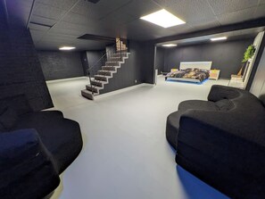 A room with a staircase, a bed, and two sofas. - 5BR Home, Pool + Game Room | Sleeps 16+ (Evansville)