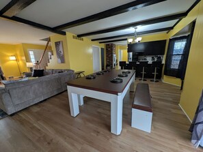 Un comedor con una larga mesa, bancos y una cocina al fondo.