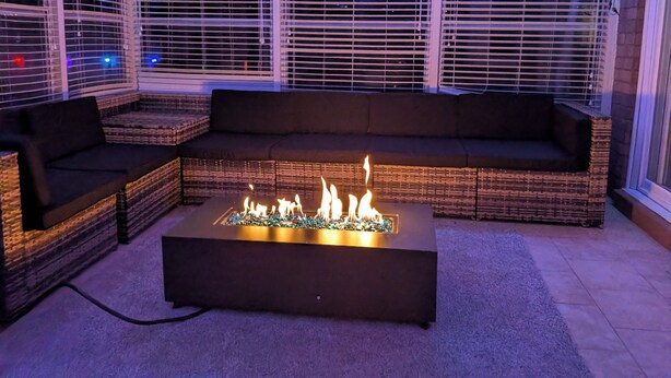 A cozy seating area with a fire feature, wicker furniture, and large windows with blinds. - 5BR Home, Pool + Game Room -- Sleeps 16+ (Evansville)