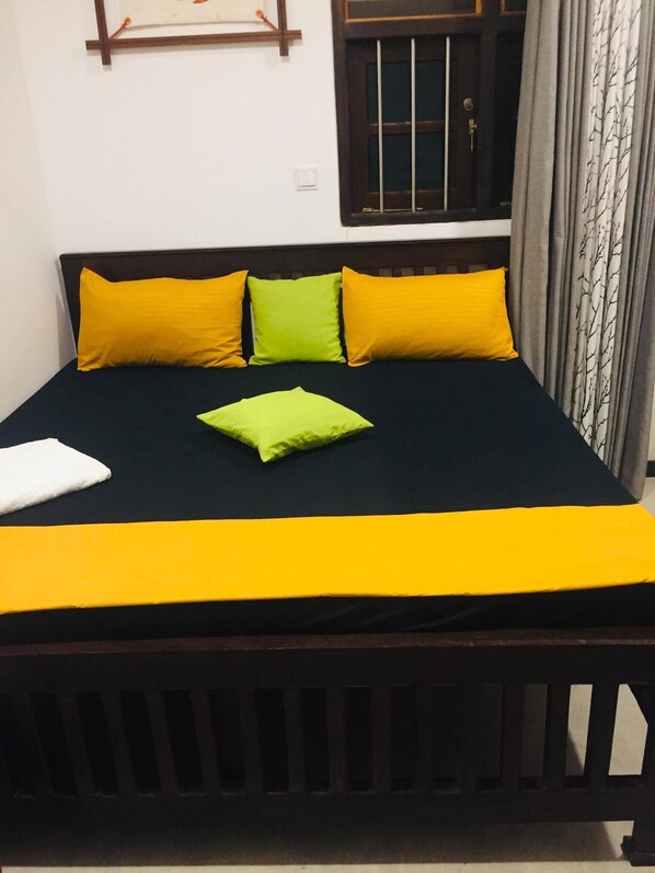 A bed with a black frame, a yellow bedspread, and three pillows in yellow, green, and white. - New white villa àhàngàmà  (Ahangama)