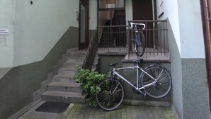 A narrow alleyway with a bicycle leaning against a wall, a staircase leading to an upper floor, and a door with a sign. - A cozy 46m² apartment in a historic tenement house, Great location! (Kraków)