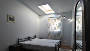 A bedroom with a skylight, a bed, a nightstand, a mirror, and a window with curtains. - A cozy 46m² apartment in a historic tenement house, Great location! (Kraków)