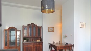 A dining area with a wooden table and chairs, a cabinet, and a hanging light fixture. - A cozy 46m² apartment in a historic tenement house, Great location! (Kraków)