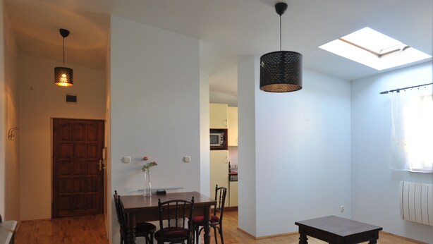 A dining area with a wooden table and chairs, a ceiling light, and a view of the kitchen through an open door. - A cozy 46m² apartment in a historic tenement house, Great location! (Kraków)