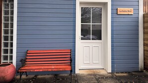 Un edificio azul con una puerta blanca y una banca afuera.