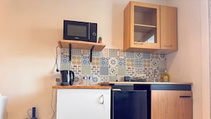 Una cocina compacta con microondas, cafetera y refrigerador pequeño.