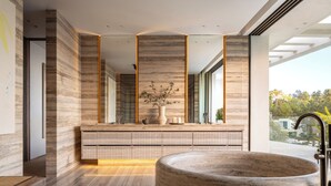 Ein modernes Badezimmer mit einer großzügigen Freisitzbadewanne, einer Duschkabine aus Glas und einem Waschtisch mit Marmorplatte.