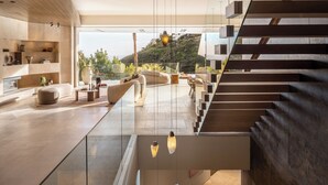 Ein modernes Interieur mit Treppe, Glastrennwand und hängenden Pendelleuchten.