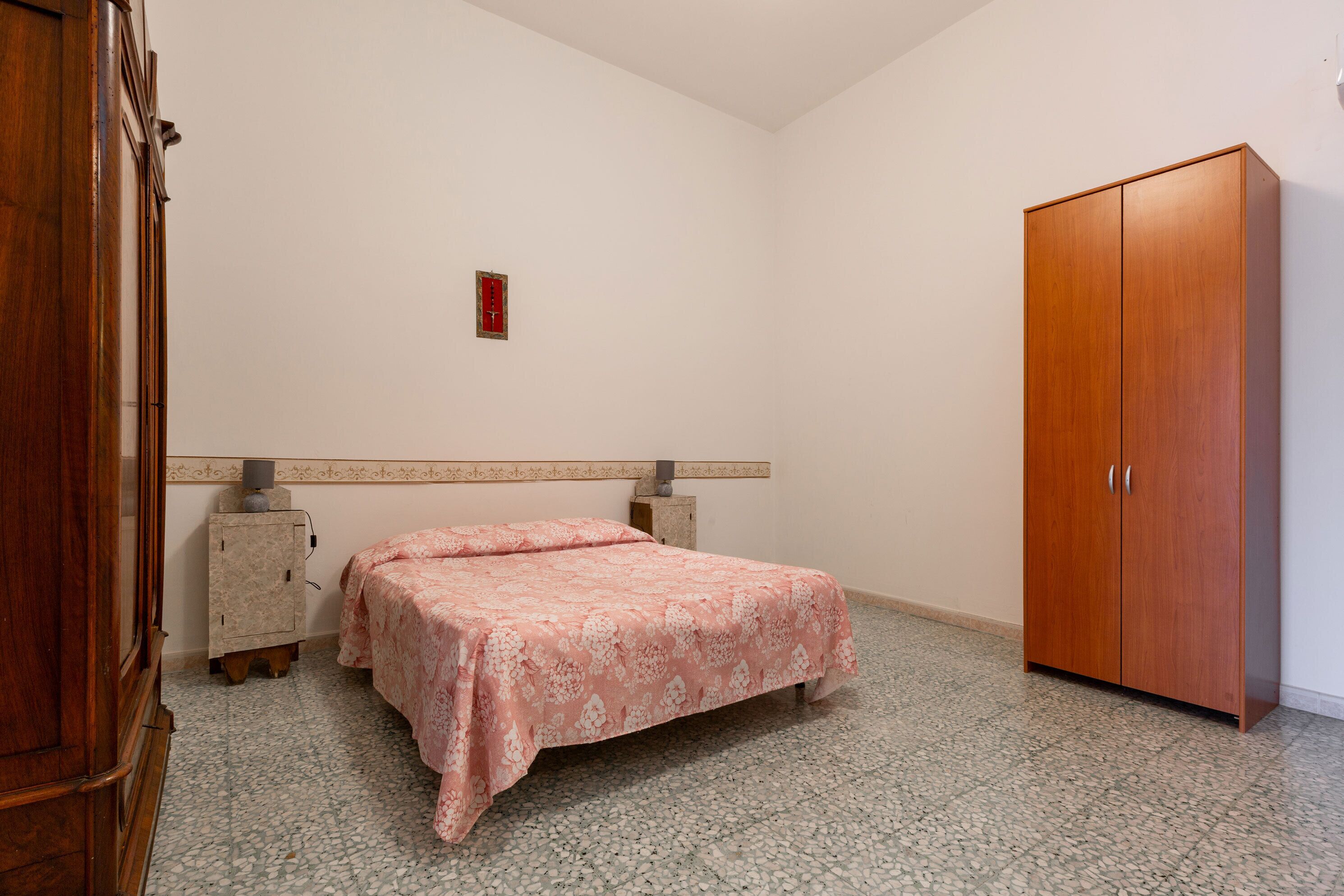 A bedroom with a bed, wardrobe, and a small cabinet.