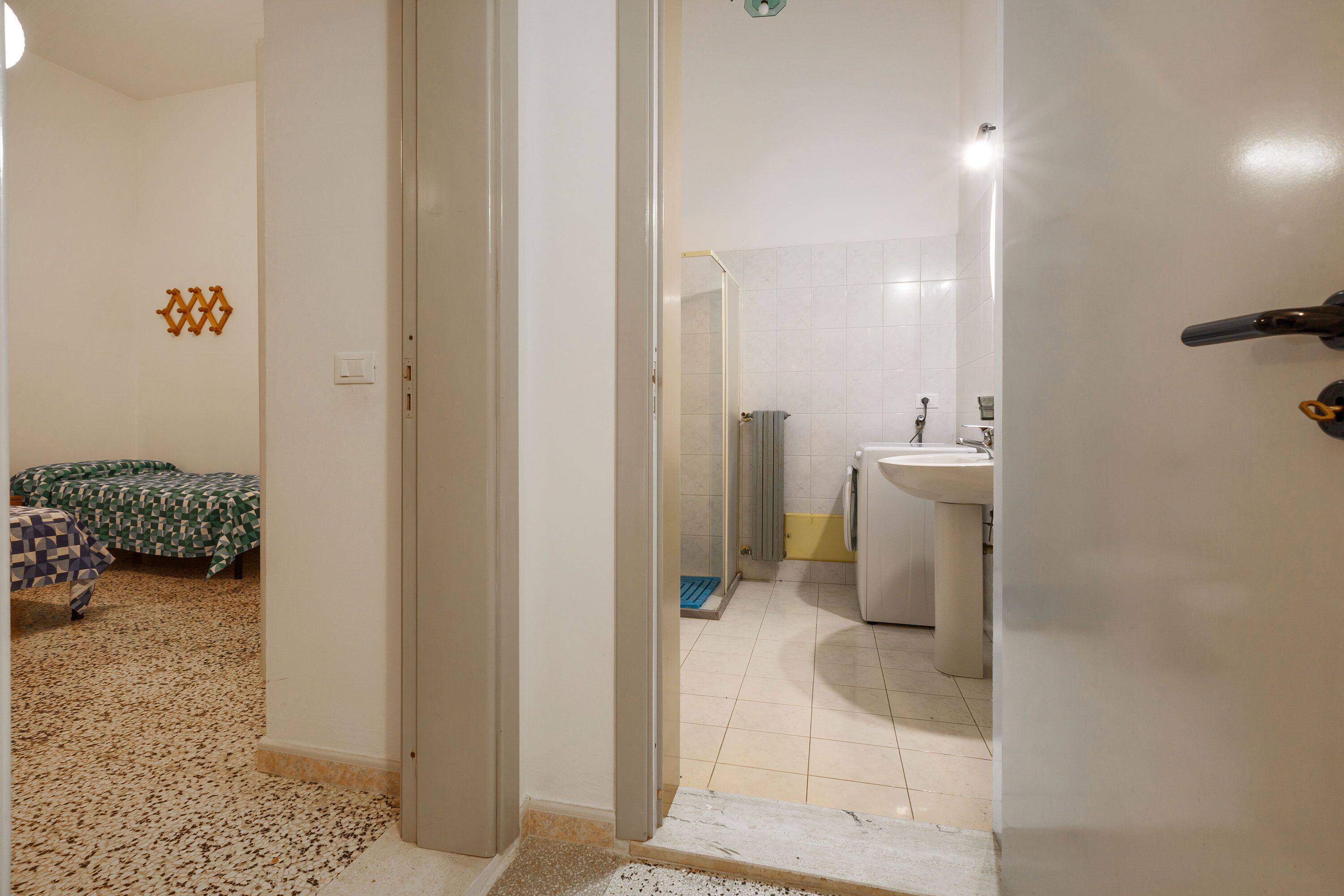 A hotel room with a bed, a bathroom with a sink and toilet, and a shower area.