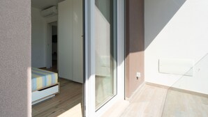 Une pièce avec un lit, une porte-fenêtre coulissante et une petite fenêtre.