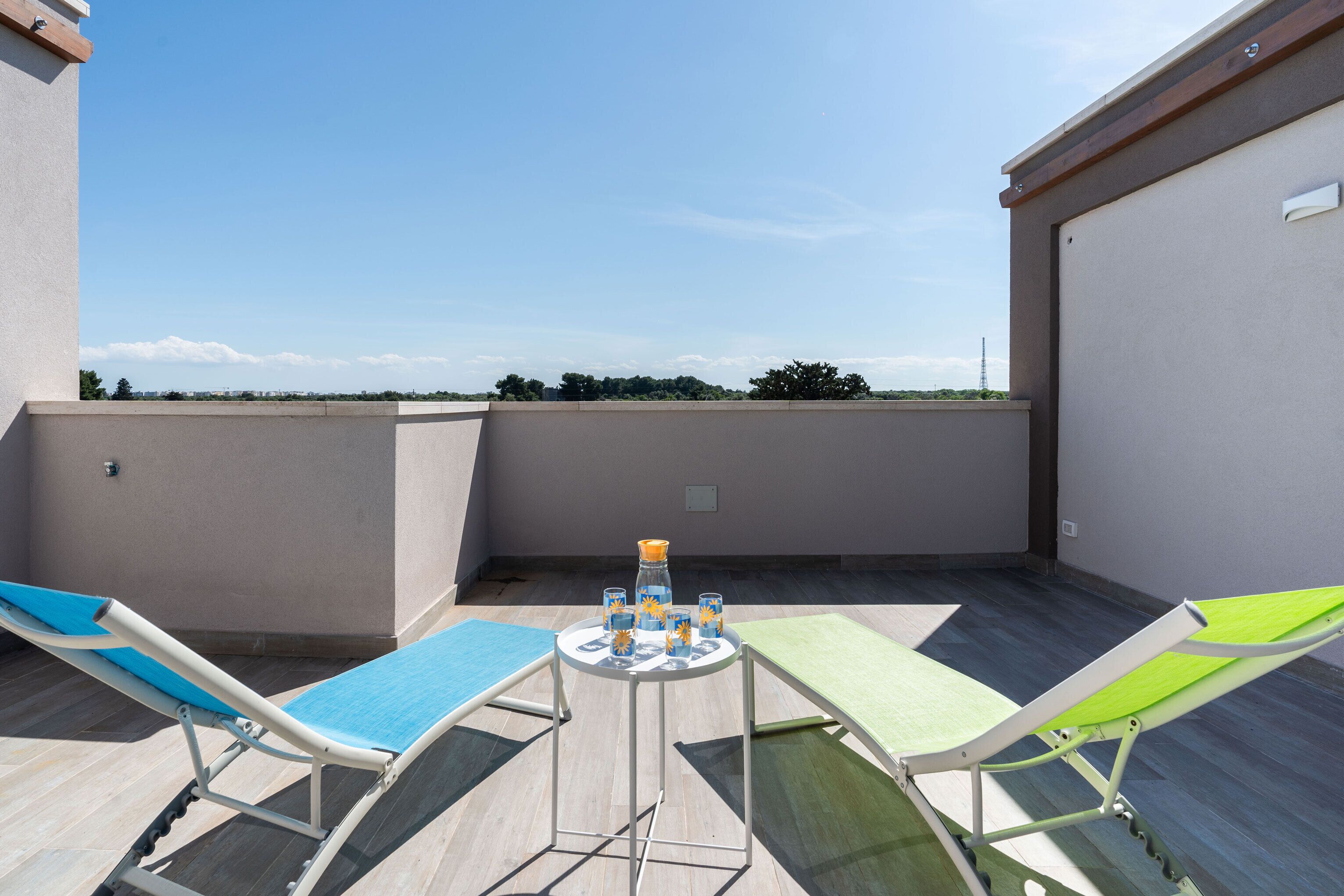 Een dakterras met twee lounge fauteuils en een tafeltje met drankjes.