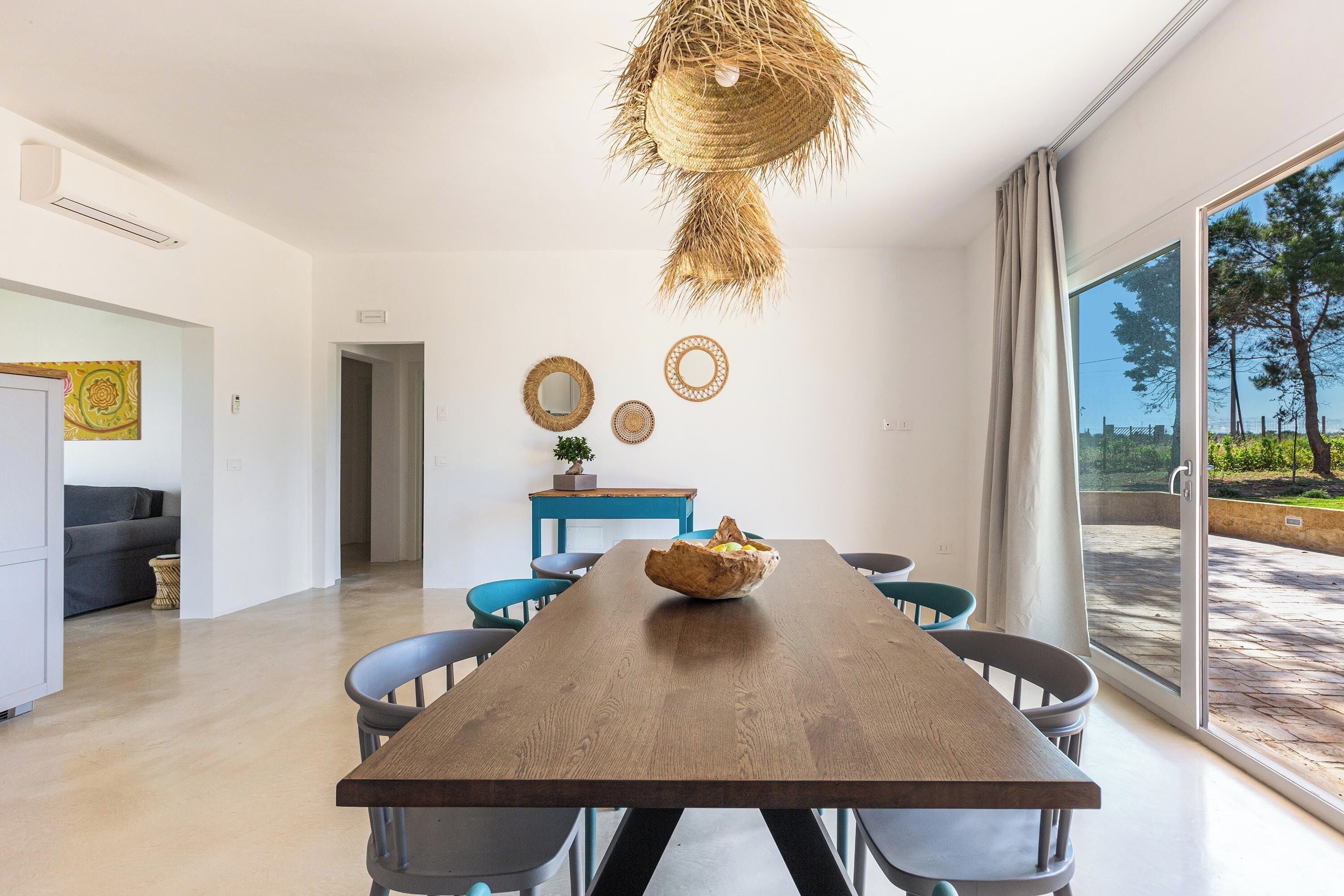 Un'area pranzo moderna con un tavolo in legno, sedie e un cesto appeso.