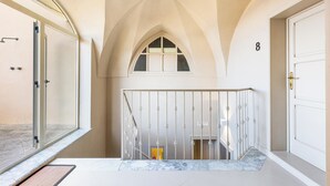 Una escalera con barandilla blanca, una puerta con el número 8 y una ventana que da a la calle.