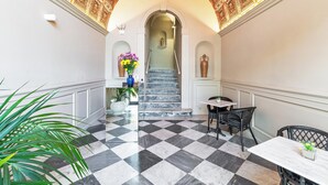 Un pasillo con piso a cuadros, una escalera y un techo decorativo.