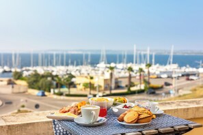A table with breakfast items and a view of a marina. - B&B Palazzo Vergine - Matrimoniale Comfort (Gallipoli)