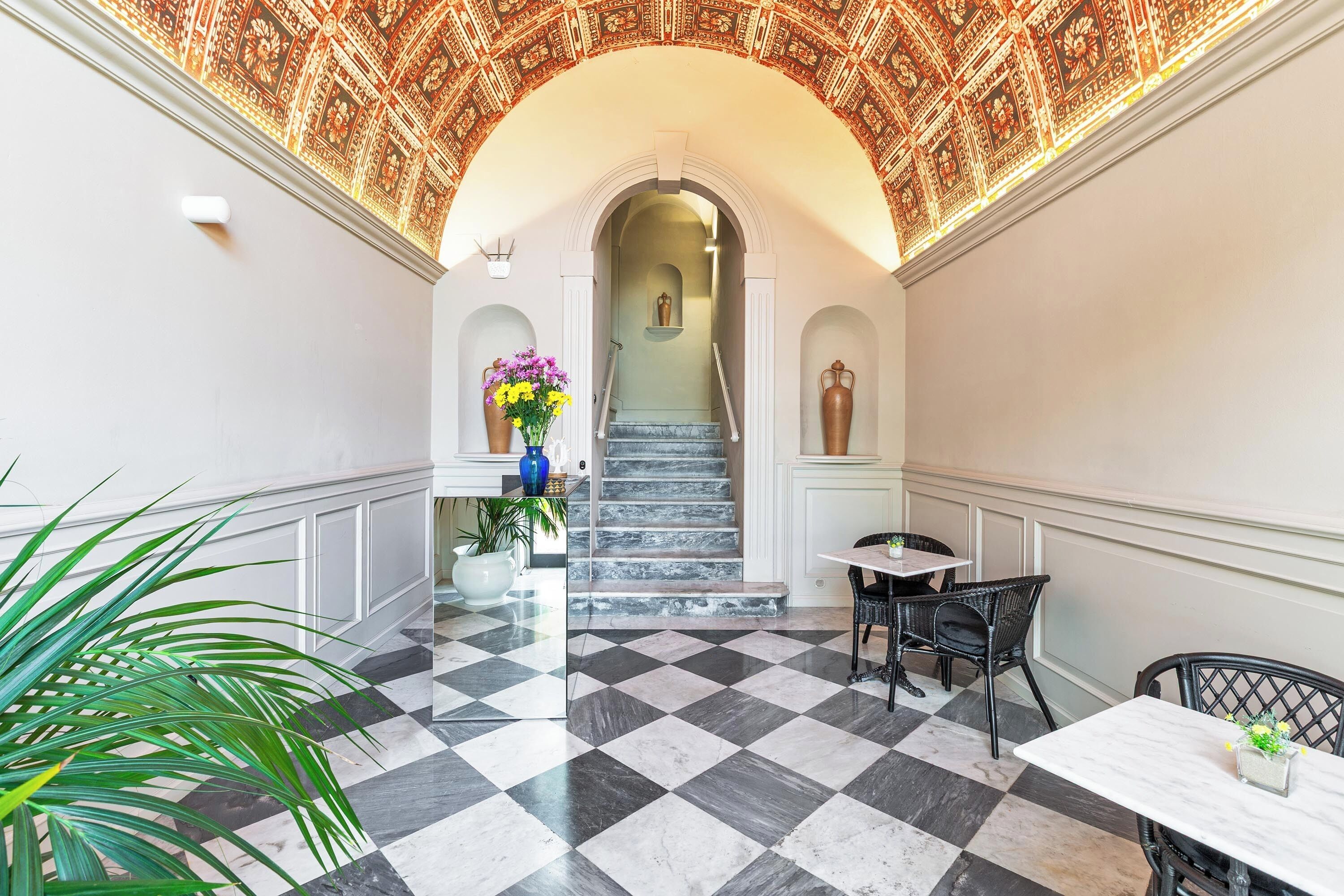 Un couloir doté d’un sol à carreaux, d’un escalier et d’un plafond décoratif.