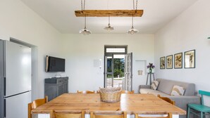 Eine moderne Küche mit einem Holztisch, Stühlen, einem Kühlschrank und einem Fernseher an der Wand.
