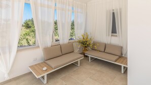 Ein Zimmer mit zwei beigen Sofas, einem kleinen Holztisch und einer Vase mit gelben Blumen.