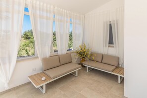 Ein Zimmer mit zwei beigen Sofas, einem kleinen Holztisch und einer Vase mit gelben Blumen.