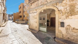 Eine enge Straße mit einem Steinhaus, das einen Rundbogen und ein Metallgitterzugang aufweist.