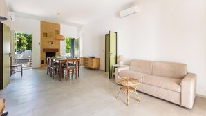 Amplia sala de estar con sofá, mesa de comedor, sillas y una mesita auxiliar.