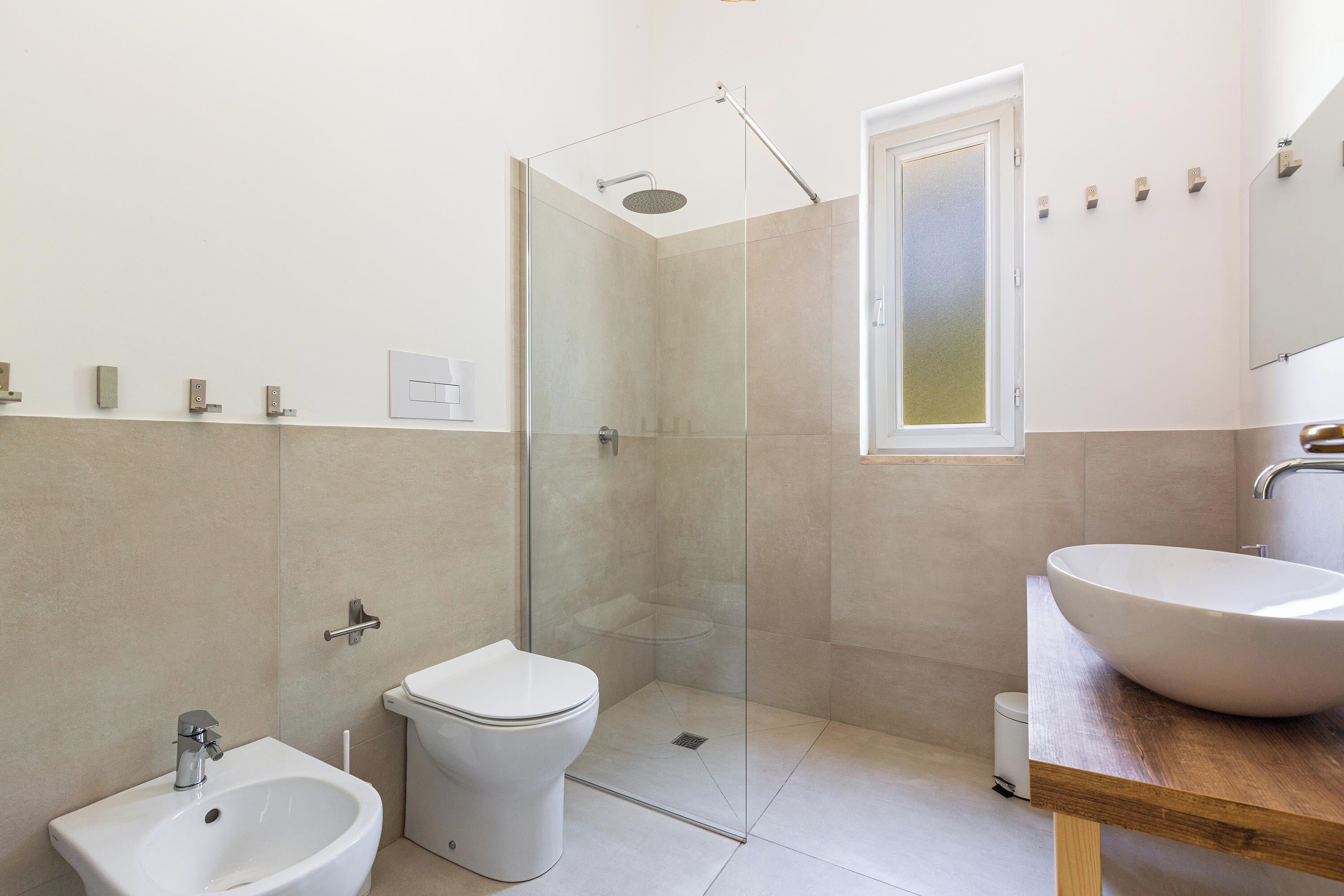 Ein modernes Badezimmer mit einer Duschkabine, einem weißen Waschbecken und einer Toilette.