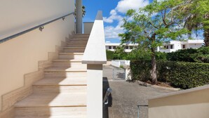 Eine Treppe führt zu einem Gebäude, im Hintergrund ein klarer Himmel und Bäume.