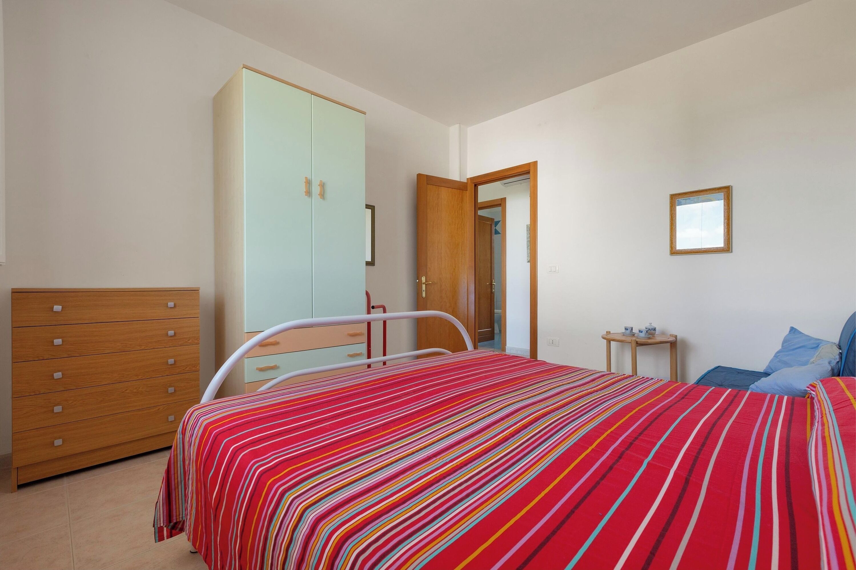 Une chambre à coucher comprenant un lit, une armoire, une table de chevet et un miroir.