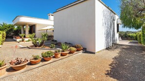 A modern building with a white exterior, surrounded by a gravel driveway and potted plants. - Villa di Carmen by BarbarHouse (Castrignano del Capo)