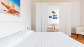 A bedroom with a large bed, a wardrobe, a chair, and a painting of a starfish on the wall. - Villa di Carmen by BarbarHouse (Castrignano del Capo)