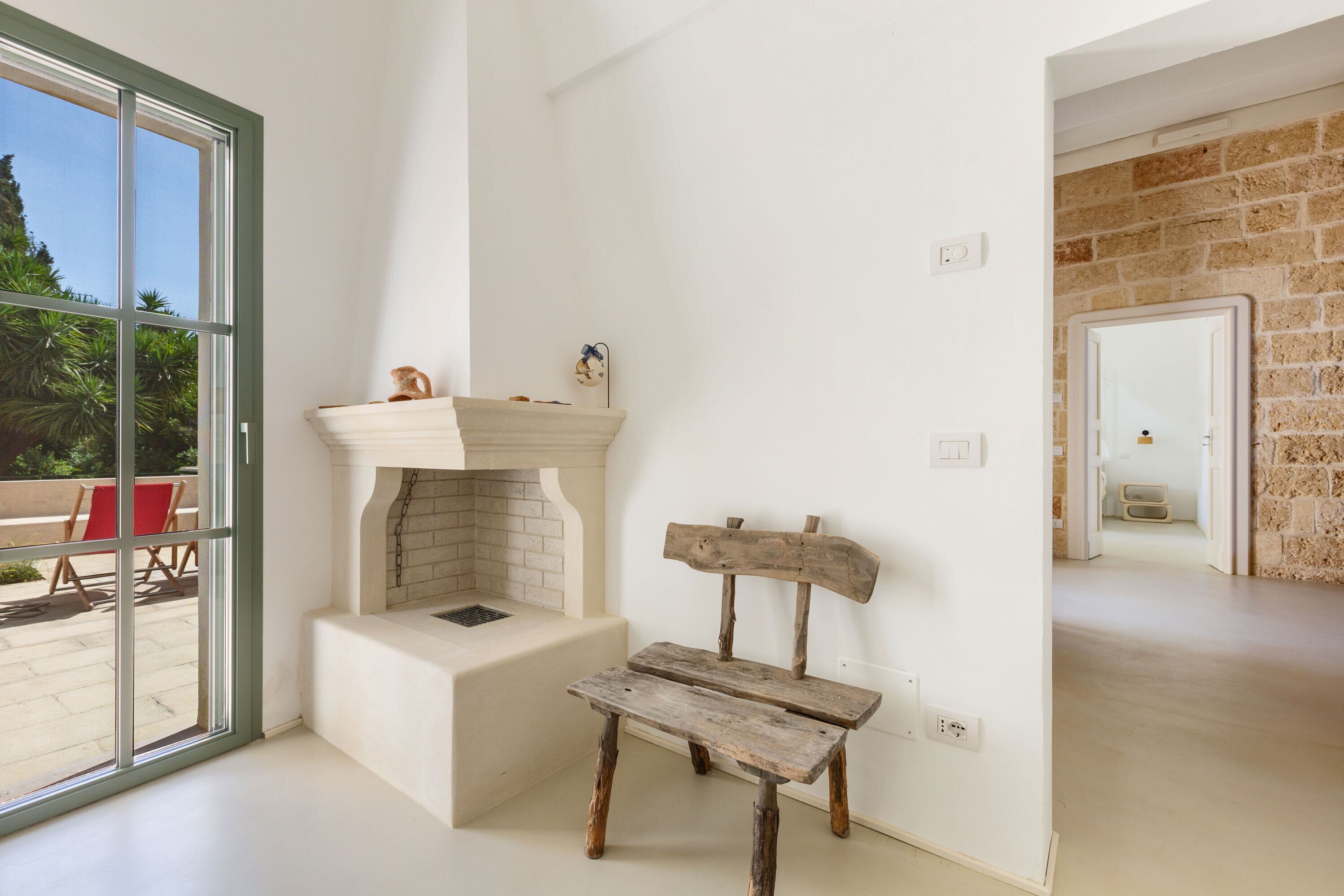 Een kamer met een open haard, een bank en uitzicht op de omgeving.