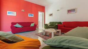 A living room with red and green sofas, a coffee table, and a patterned rug. - Nando`s Bellavista House By BarbarHouse (Porto Cesareo)