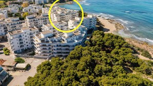 Vista aèria d'una zona residencial costanera amb edificis de diversos pisos, una platja i vegetació abundant.