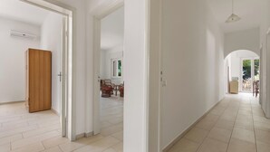 Un'ampia sala con un'armadio in legno, un'area da pranzo con sedie in vimini e vista sull'esterno.