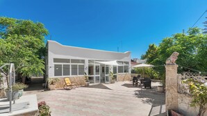 A modern building with a flat roof, large windows, and a paved patio area with potted plants. - Villa Lina by BarbarHouse (Leporano)