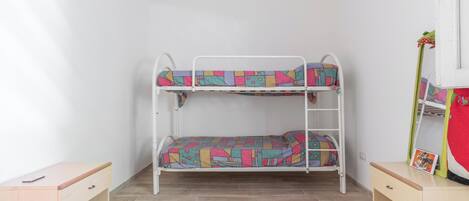 Un lit superposé avec une literie aux couleurs vives, un petit bureau et un miroir sur le côté droit.