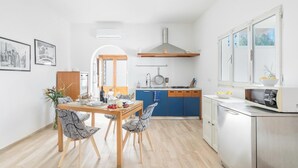 A modern kitchen with wooden cabinets, a stainless steel refrigerator, and a dining area with a table and chairs. - Villa Lina by BarbarHouse (Leporano)