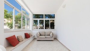 A corner room with a sofa and a bench against the wall, large windows, and a tiled floor. - Villa Lina by BarbarHouse (Leporano)