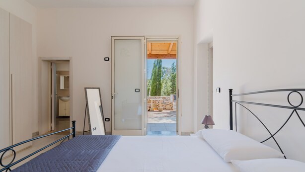 A bedroom with a bed, a door leading to an outdoor area, and a view of trees. - Villa Amelia by BarbarHouse (Torre Lapillo)