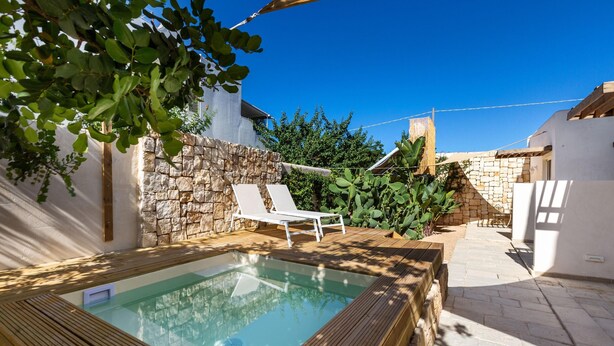 Ein Schwimmbecken mit Holzterrasse und Steinmauer.