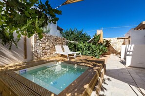 Una piscina con muelle de madera y pared de piedra.