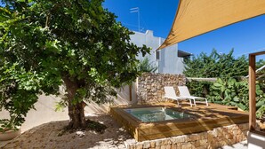 Ein privater Poolbereich im Freien mit Steinmauer, Baum und Sonnensegel.