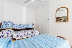 Ein Schlafzimmer mit einem Bett, einem Holzkopfstück, einem an der Wand befestigten Spiegel und einer Tür.