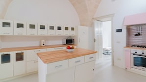Una cucina moderna con mobili bianchi, un piano di lavoro in legno, un forno a microonde, un fornello a gas e una ciotola di frutta.