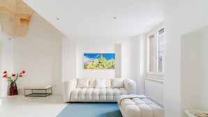 Un soggiorno moderno con un divano bianco, un tappeto blu e un quadro che raffigura un cactus.