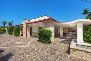 Una casa con un patio de piedra, techo rojo y un pequeño jardín.